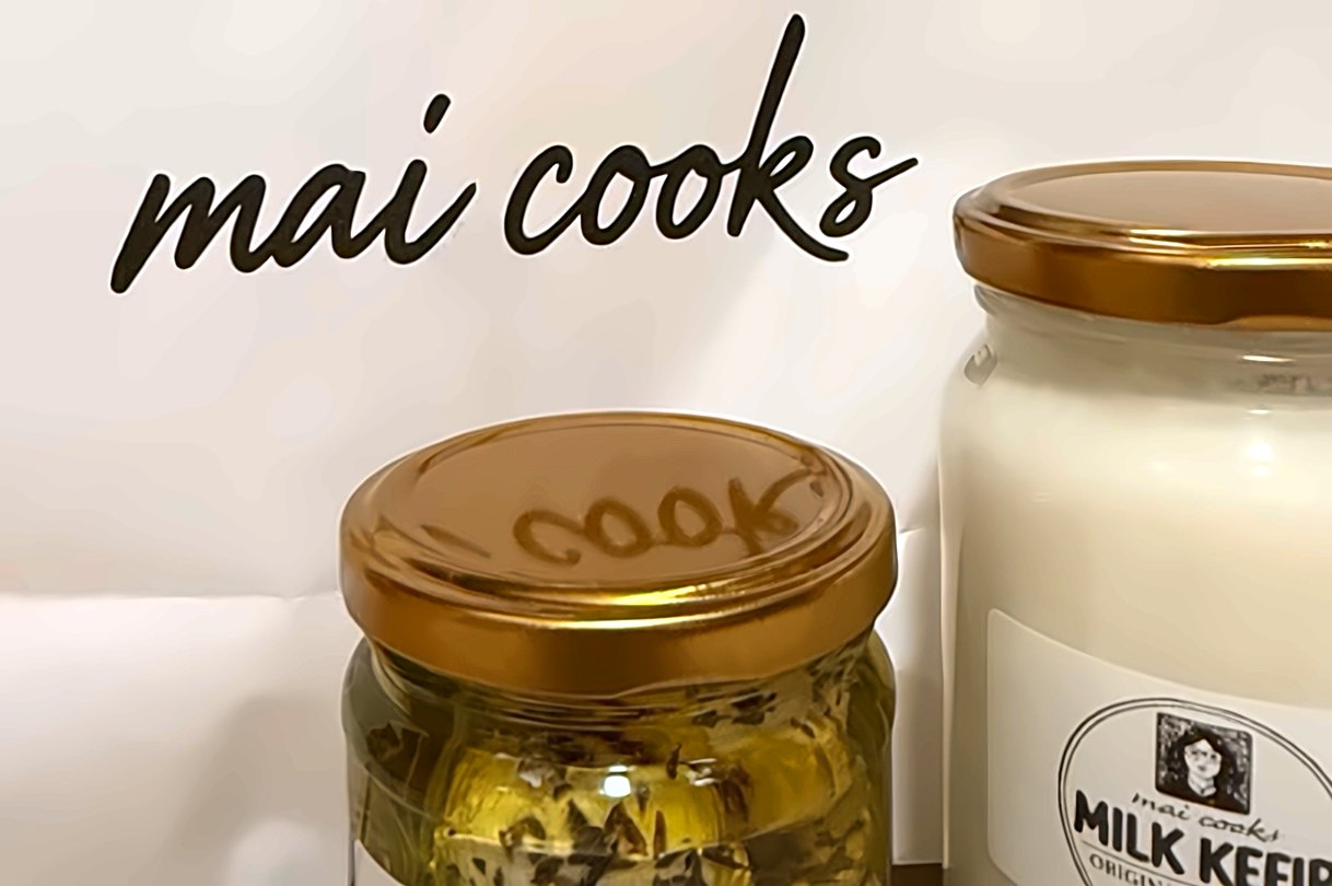The mai cooks paper bag with a jar of labneh balls and a jar of milk kefir in front of it